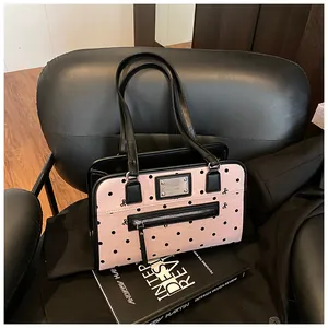 Détail d'un sac à bandoulière rose à pois avec garniture noire et poche zippée argentée
