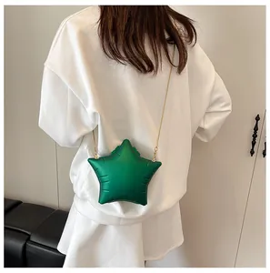 Detail view of a green star-shaped crossbody bag with a gold chain on a model