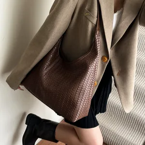 Close-up of a large dark brown woven leather hobo bag with intrecciato pattern