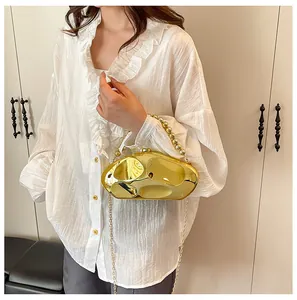 Dettaglio pochette dorata a specchio con texture concava irregolare e manico di perle