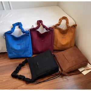 Detail showing five colors of suede tote bags with pleated shoulder straps and front pockets