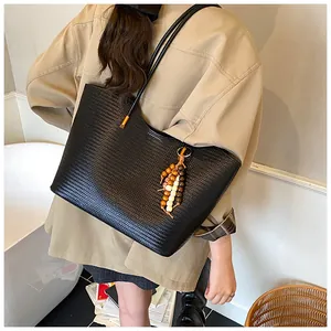 Detail of black woven tote bag featuring a decorative wooden bead tassel and long handles