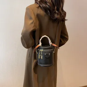 Detail of black leather bucket bag with leopard scarf and gold double zipper lock