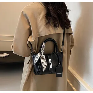 Detail of black leather bucket bag with silver twist lock and chic polka dot scarf