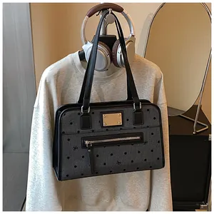 Détail d'un sac gris à pois avec nœuds noirs, plaque dorée et poche zippée avant