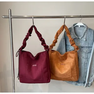 Detail of vintage suede tote bags in burgundy and tan with ruched handles and front pocket