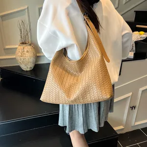 Detail of light brown woven hobo bag showing intricate texture and adjustable strap