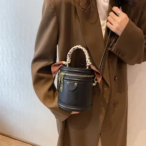 Detail of black mini bucket bag with silk scarf handle and gold chain accessory