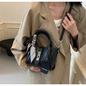 Detailed shot of black textured bucket bag with decorative scarf and silver hardware