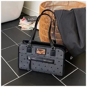 Détail du sac bandoulière en toile grise à pois avec anses en cuir et plaque logo en métal