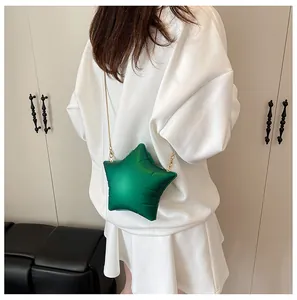 Detail of a star-shaped green bag with gold snake chain on a white dress