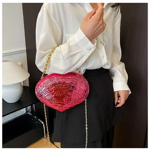 Détail de la pochette coquillage fuchsia avec poignée en perles dorées et chaîne
