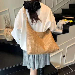 Detail of a large khaki woven tote bag showing the honeycomb texture and wide strap