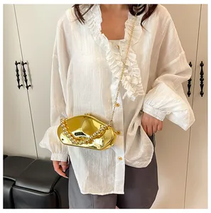 Borsa a mano dorata effetto specchio con manico di perle e tracolla a catena vista su modella