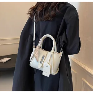 Close-up of beige bucket bag with plaid silk scarf and detachable leather strap