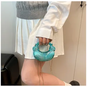 Detail einer metallischen Crescent-Handtasche in Seeblau mit Wellenstruktur und Goldkette