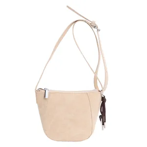 Minimalistische beige Wildleder Umhängetasche mit feiner Textur und gewebtem Anhänger