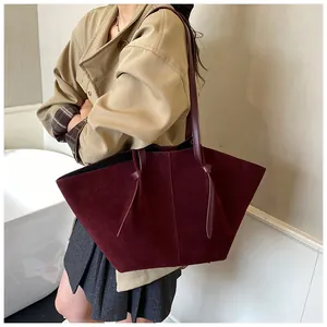 Detail of burgundy suede tote bag featuring elegant knotted shoulder strap on trench coat
