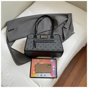 Vue détaillée du sac gris à pois avec iPad et téléphone pour comparer la taille