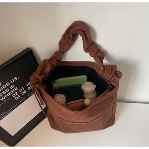 Detail of brown suede handbag showing large capacity for tablet and daily items
