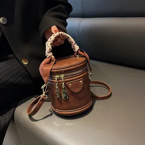 Detail of a brown cylindrical bucket bag featuring leopard print scarf handle wrap