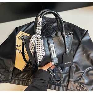 Detail of black leather bucket bag featuring silver twist lock and decorative silk scarf
