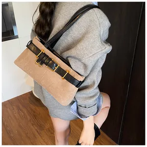 Détail d'un sac porté épaule en daim marron avec lanières en cuir noir et boucles dorées