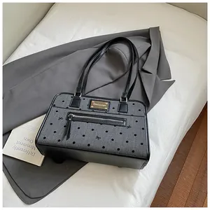 Détail du sac gris à pois avec broderie de nœud et logo de la marque en métal doré