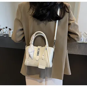 Model wearing a creamy white bucket bag with silk scarf handle detail and metal lock