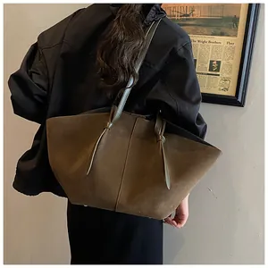 Détail du sac cabas en suédine montrant les nœuds de bandoulière et la texture olive