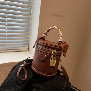 Detail of vintage brown bucket bag with decorative silk scarf handle and metal lock zipper
