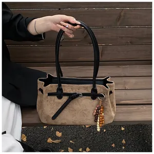 Detailaufnahme einer braunen Wildleder-Tragetasche mit einem Vintage-Holzperlen-Anhänger
