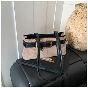 Détail du sac sous le bras en daim avec brides en cuir noir et boucle en métal doré