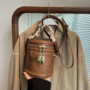 Close-up of retro brown bucket bag with gold hardware and silk scarf handle detail
