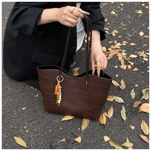 Detail of dark brown woven tote bag with wood bead tassel and wavy edge design