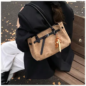 Detail der braunen Vintage-Matte-Tasche mit Perlenquaste und Schnalle auf einer Holzbank