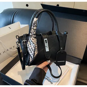 Detail of black textured bucket bag with silver twist lock and decorative silk scarf handles