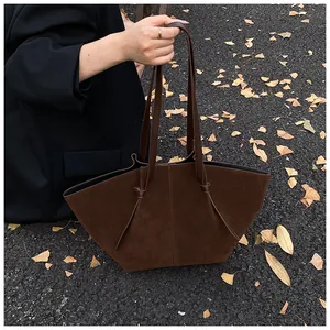 Detail of dark brown faux suede tote bag with stylish knotted handle on autumn pavement