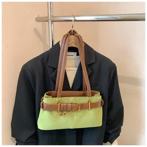 Détail du sac sous le bras en daim vert avec ceinture en cuir marron et boucle dorée