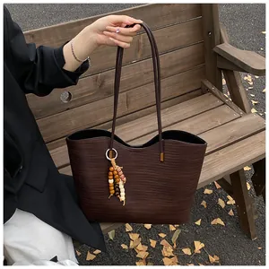 Close-up of woven coffee tote bag featuring bohemian wooden beads on park bench
