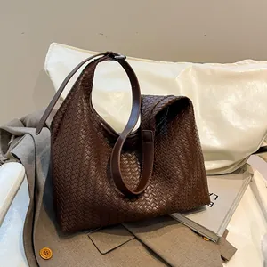 Close-up of dark brown woven leather tote bag with Intrecciato texture and adjustable strap