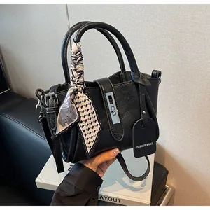 Detail of black pebbled leather bucket bag with decorative scarf handle and silver twist lock