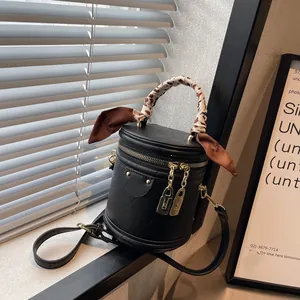 Detail of black cylinder bag with leopard print scarf handle and gold lock hardware
