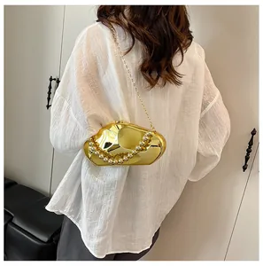 Dettaglio della borsa clutch in metallo dorato con grande manico in perle e catena