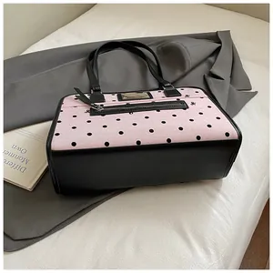 Détail du sac Boston en toile à pois roses avec garniture en cuir et poche extérieure zippée