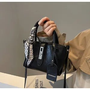 Detail of black faux leather bucket bag with checkered scarf and silver twist lock