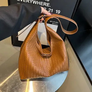 Detailed view of caramel brown woven leather texture on a large capacity hobo shoulder bag