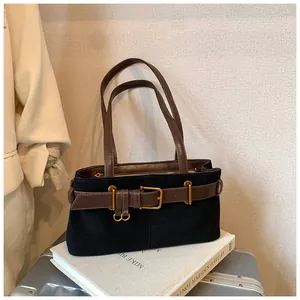 Détail du sac sous l'aisselle en daim noir avec boucle décorative en cuir marron élégante