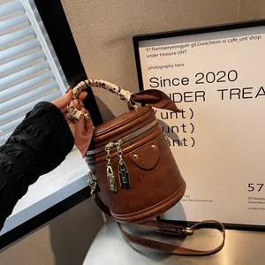 Close-up of brown bucket bag with leopard print silk scarf handle and gold lock zippers