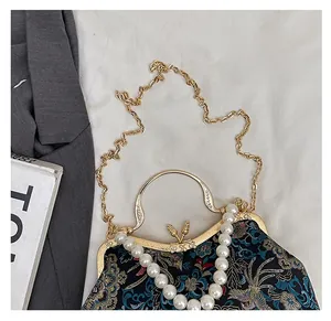 Close-up of vintage shell bag with floral embroidery and pearl chain handle detail